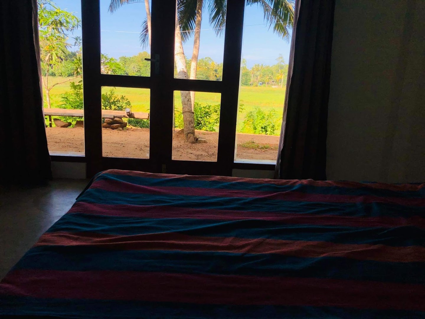 Rice-field view through dark timber-framed bedroom windows