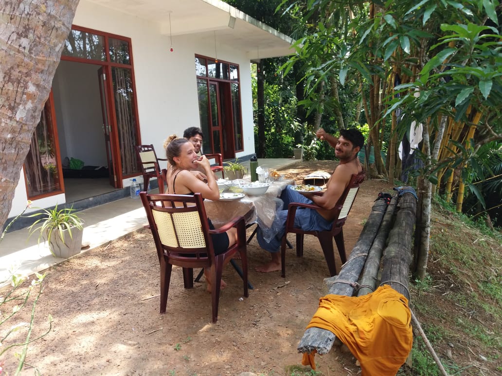 People sharing a meal at an outdoor table beside the veranda